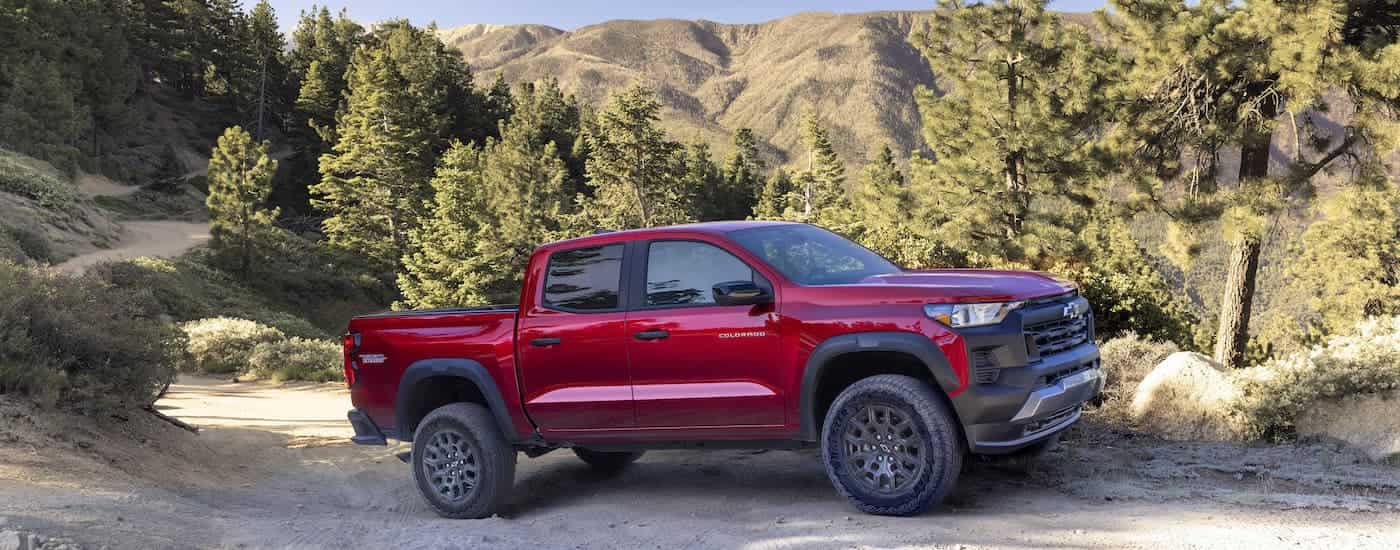 A red 2023 Chevy Colorado Trail Boss is shown from the side on a trail.