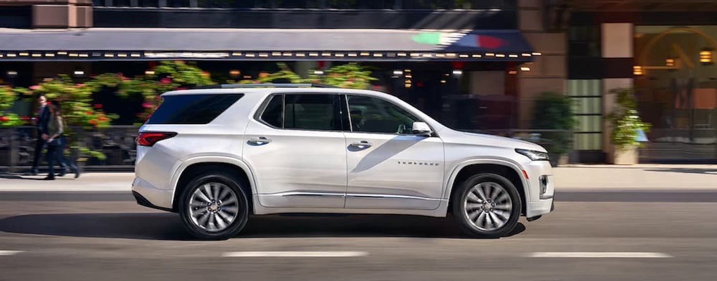 A white 2023 Chevy Traverse is shown from the side on a city street.