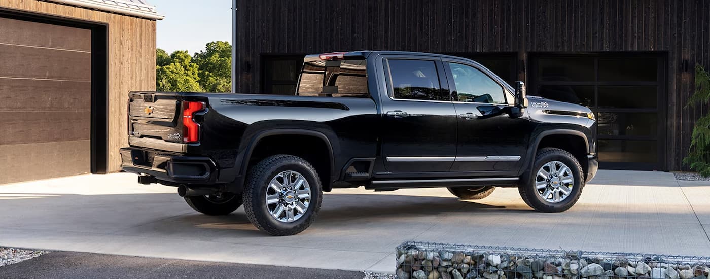 A black 2024 Chevy Silverado 2500HD High Country for sale is shown from the side parked in a driveway.