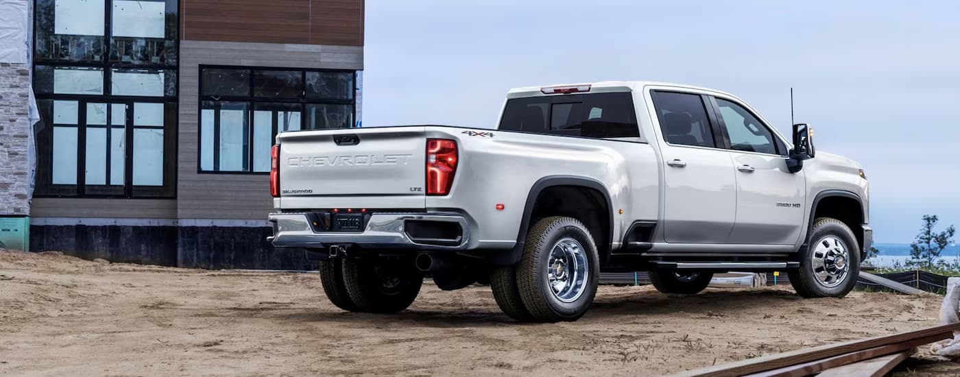 A white 2024 Chevy Silverado 3500HD is shown from a rear angle parked on a construction site.