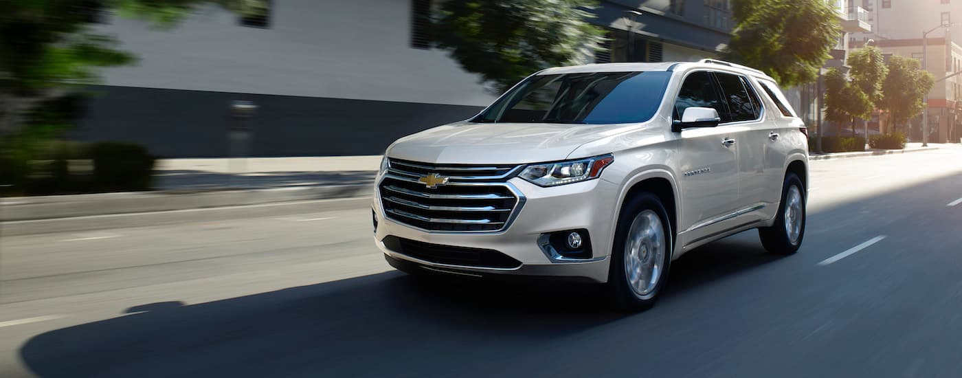 A white 2019 Chevy Traverse is shown driving through a city after leaving a Conroe used Chevy dealer.