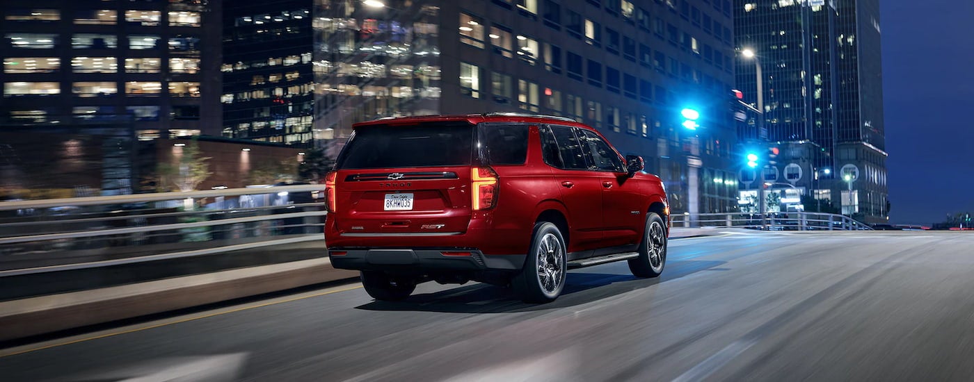 A red 2022 Chevy Tahoe RST is shown from a rear angle driving through a city.