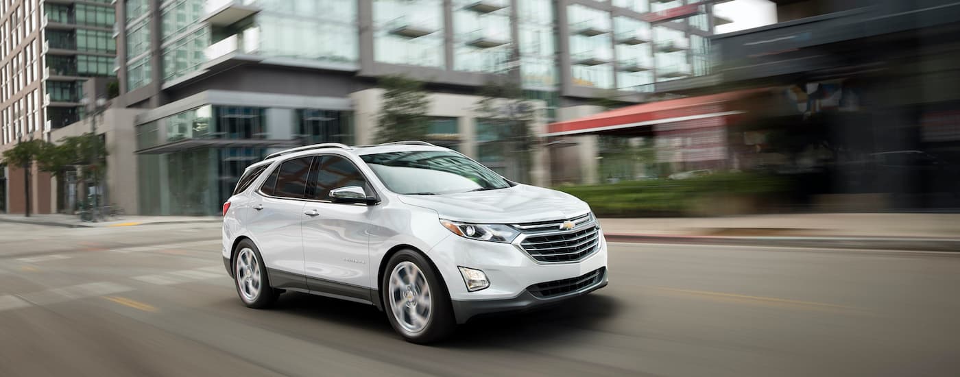 A white 2019 Chevy Equinox is shown driving on a city street.