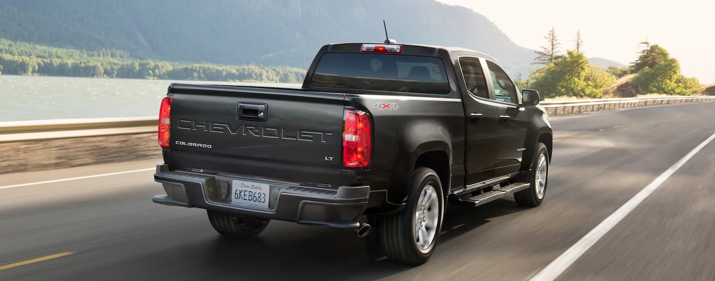 A black 2022 Chevy Colorado LT is shown from the rear driving on an open road.
