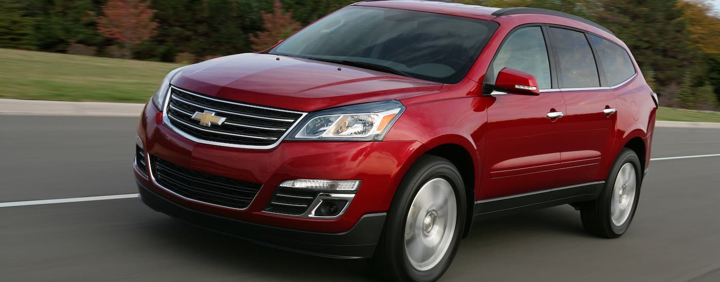 A red 2017 used Chevy Traverse is driving on a rural road.