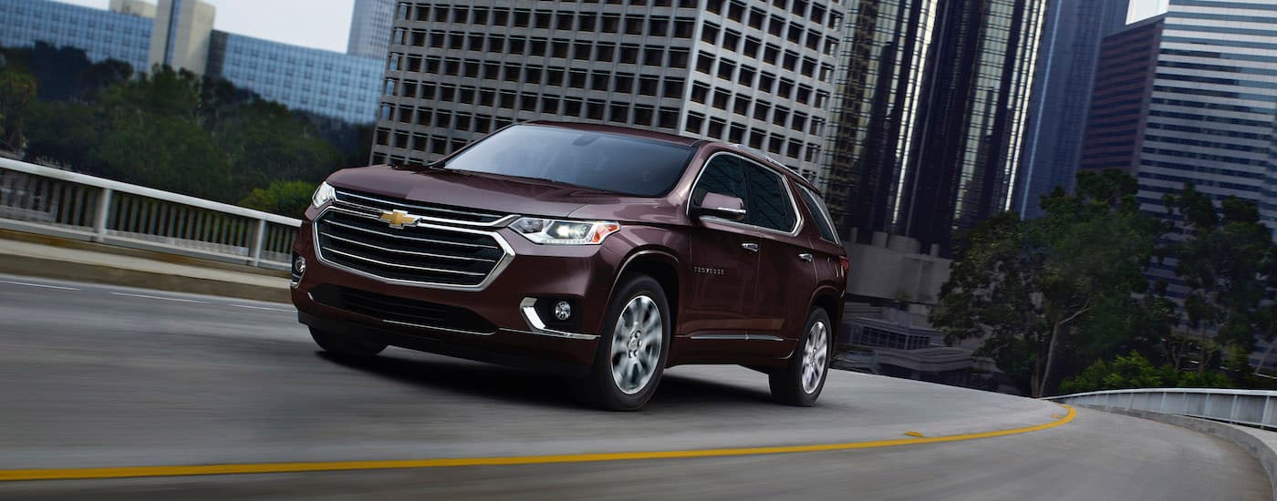 A maroon used 2020 Chevy Traverse for sale near The Woodlands is shown during a test drive on a highway.