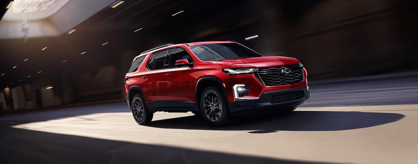 A red 2022 Chevy Traverse RS is shown driving on a city street.