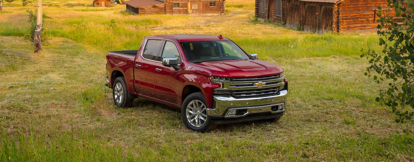 A red 2019 Chevy Silverado 1500 Z71 is parked in front of a cabin and a barn.