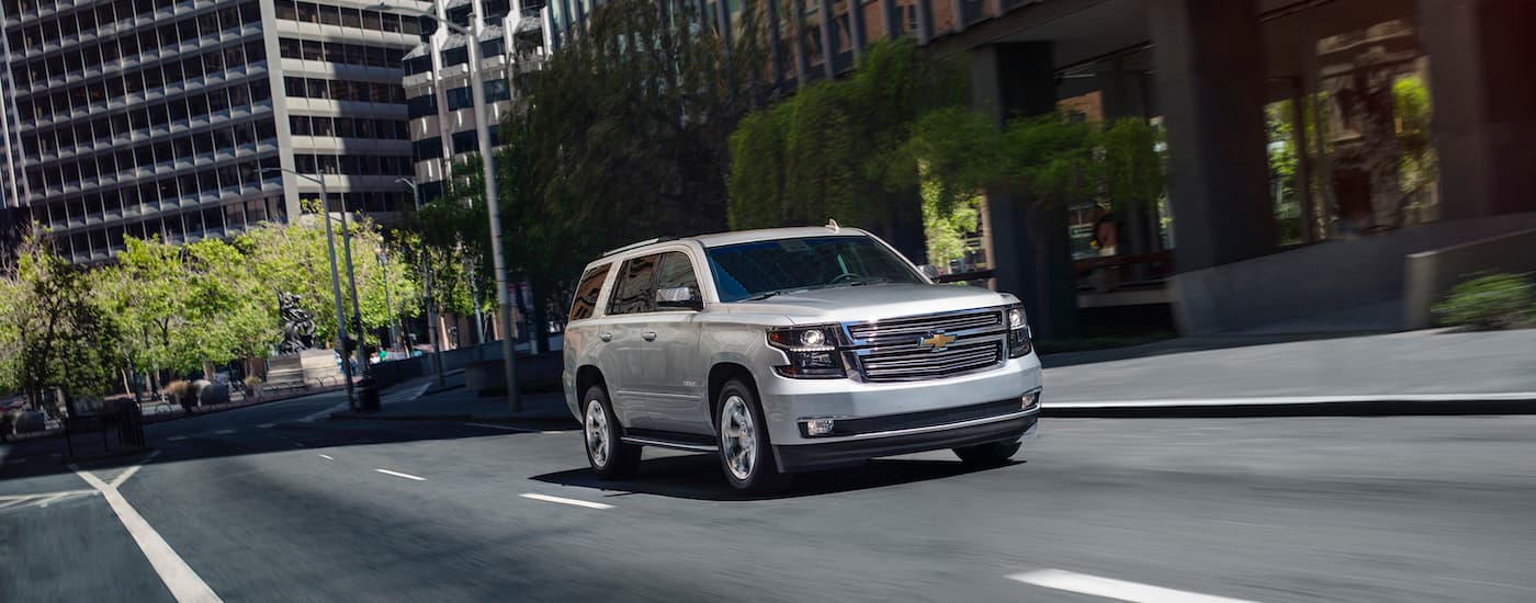 A silver 2020 Chevy Tahoe is shown driving on a city street.