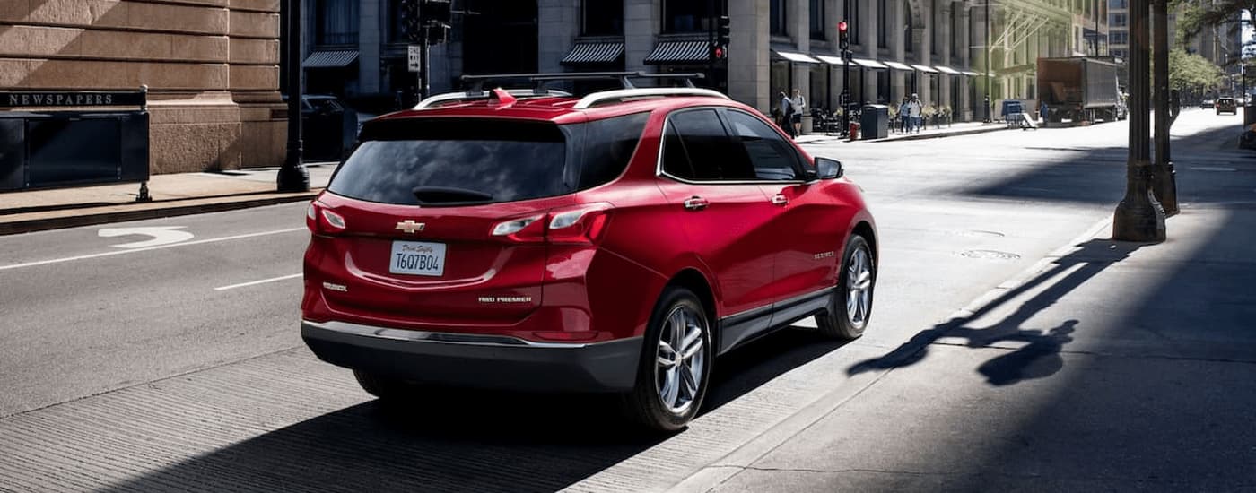A red 2021 Chevy Equinox is shown from the rear parked on the side of a city street.