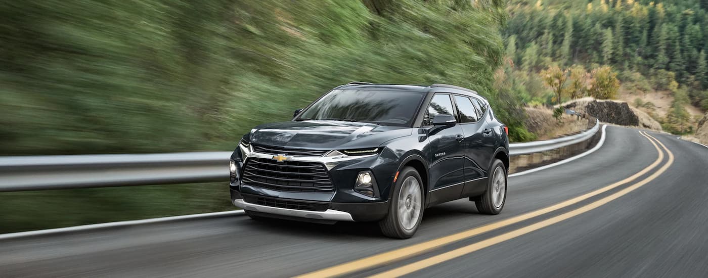 A black 2022 Chevy Blazer is shown driving on an open road after viewing used SUVs for sale.