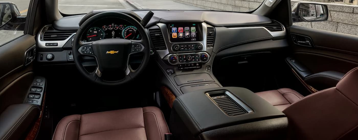 The black and brown interior of a 2020 Chevy Suburban shows the steering wheel and center console.