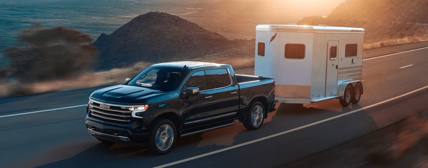 A black 2022 Chevy Silverado 1500 High Country is shown towing an enclosed trailer.
