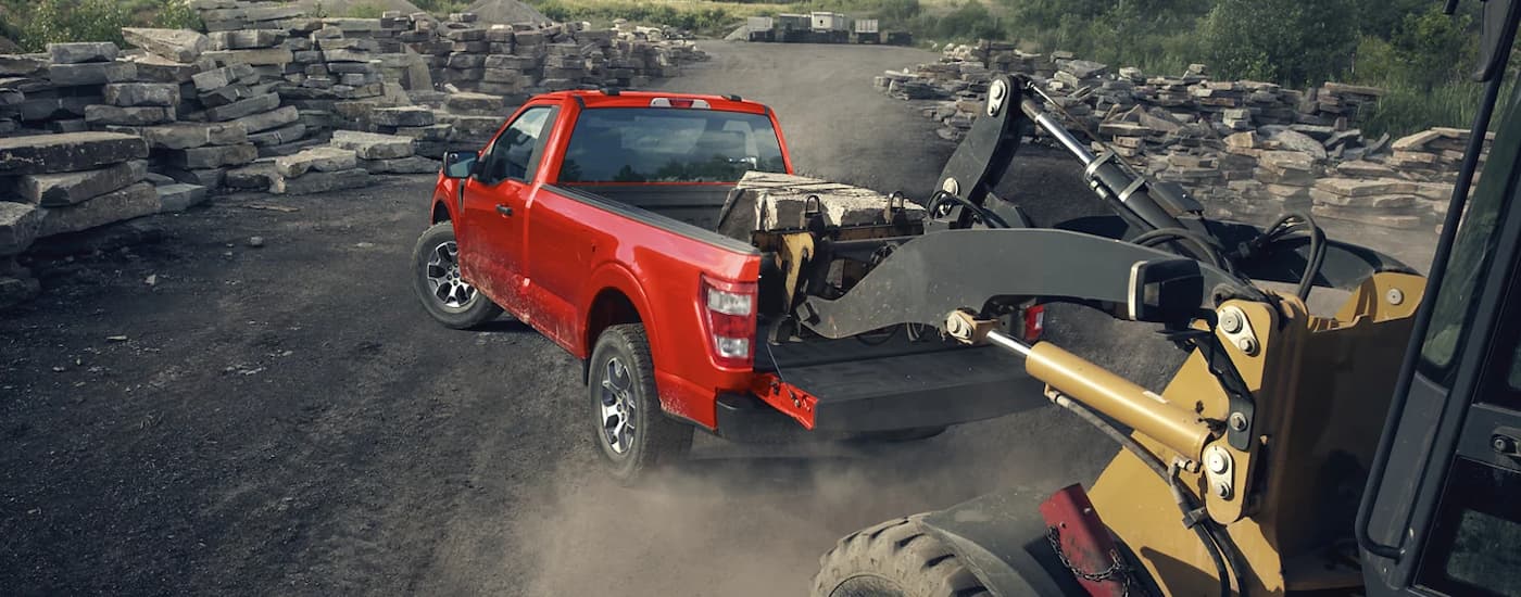 A red 2022 Ford F-150 XL is shown from the rear being loaded with rocks.
