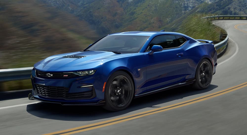 A blue 2021 Chevy Camaro is driving on a mountain road after leaving a Chevy dealer near me.