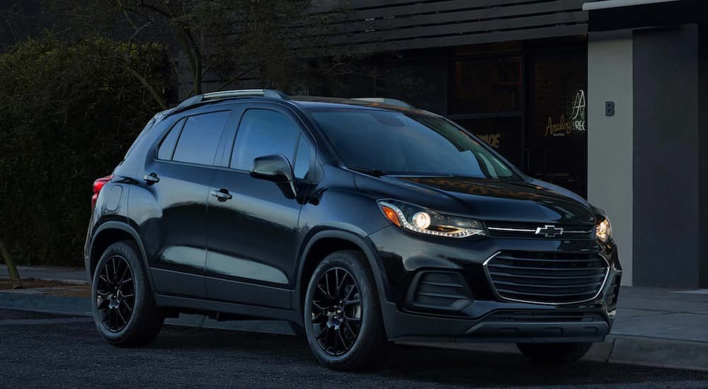 A black 2021 Chevy Trax is parked on a dark city street.