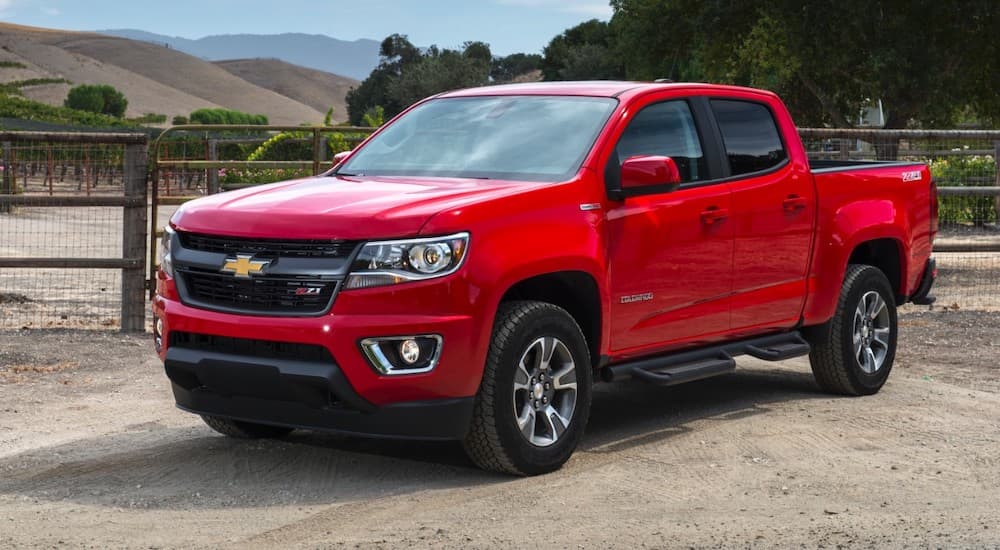 A red 2017 Chevy Colorado is parked at a farm in front of fencing.