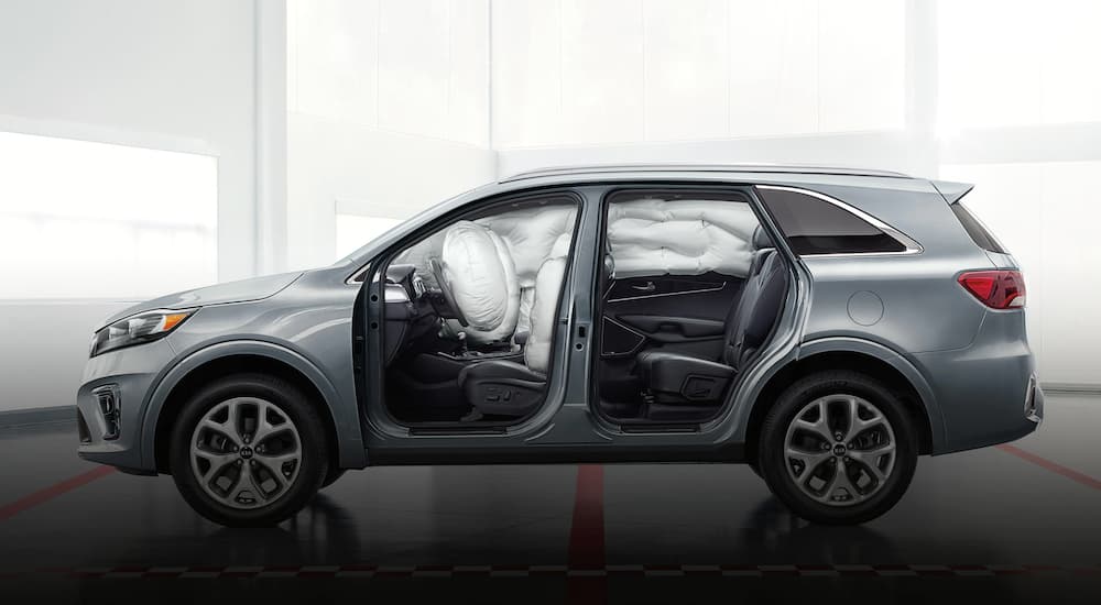 A silver 2020 Kia Sorento is shown from the side with no door to display the deployed air bags.