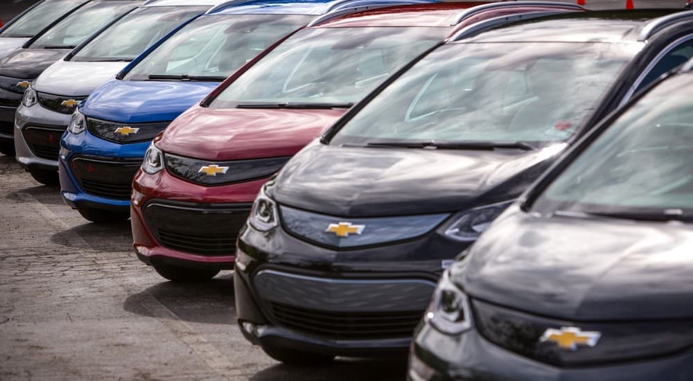 A line of used Chevy EVs, 2017 Bolt EVs, are in a parking lot.