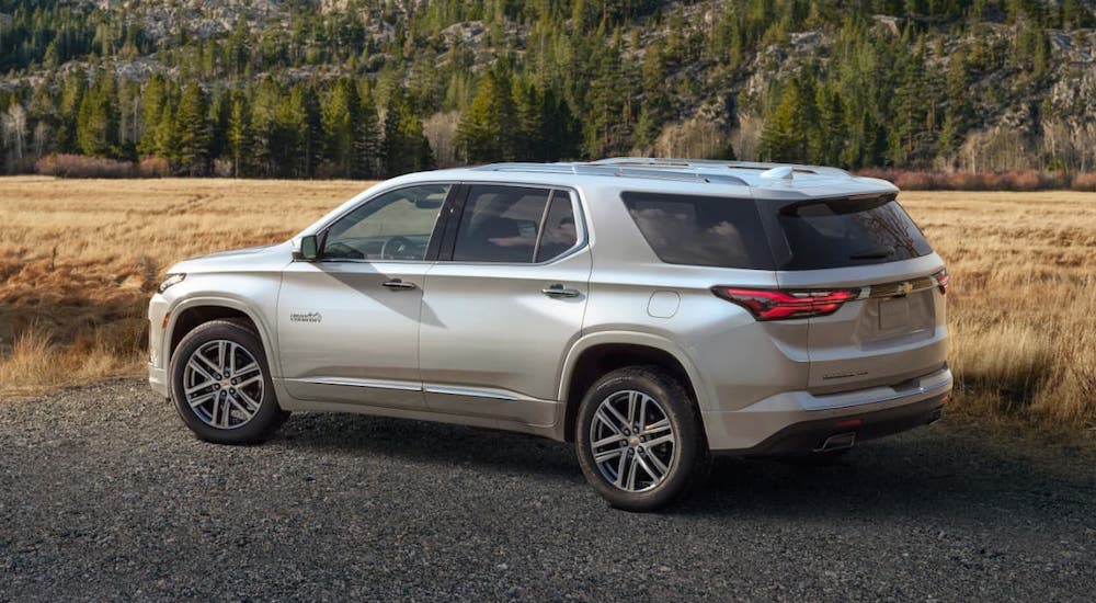 A white 2022 Chevy Traverse High Country is parked in front of yellow grass and mountains.
