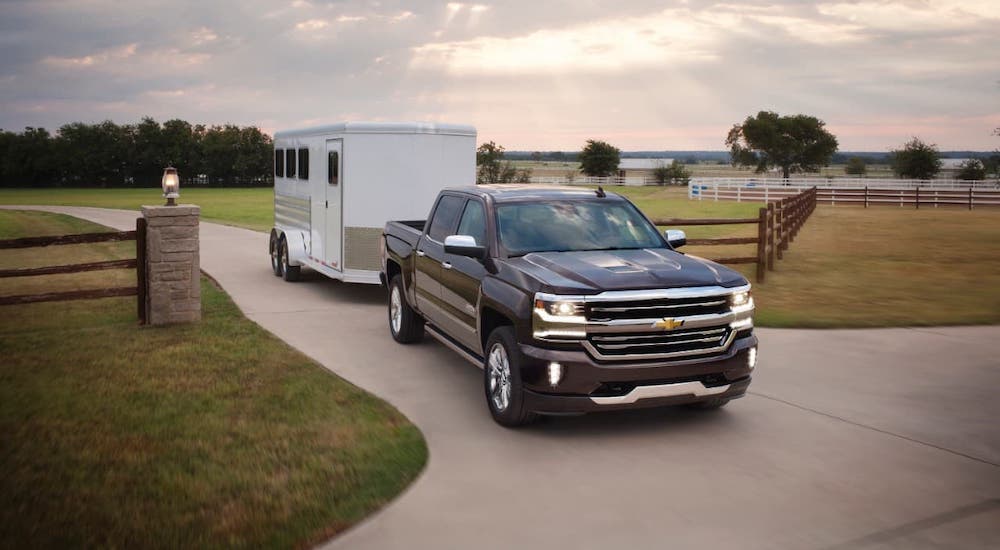 A black 2017 Chevy Silverado High Country is towing a white enclosed trailer.