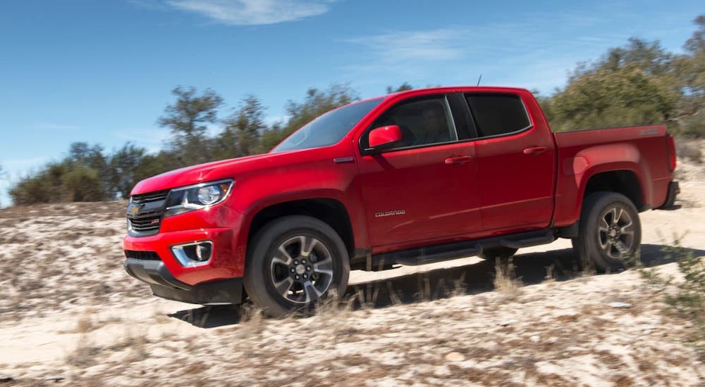 A red 2019 Chevy Colorado is driving on a sandy trail.