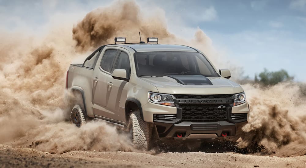 A tan 2021 Chevy Colorado is driving through sand after leaving a Texas Chevy dealer.