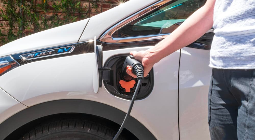 A popular Chevy EV, a white 2020 Chevy Bolt EV, is shown being charged.