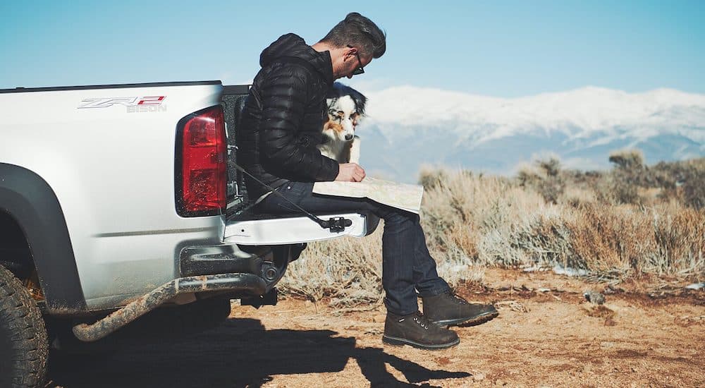 A man and dog are shown sitting on the tailgate of a 2019 Chevy Colorado ZR2 Bison.