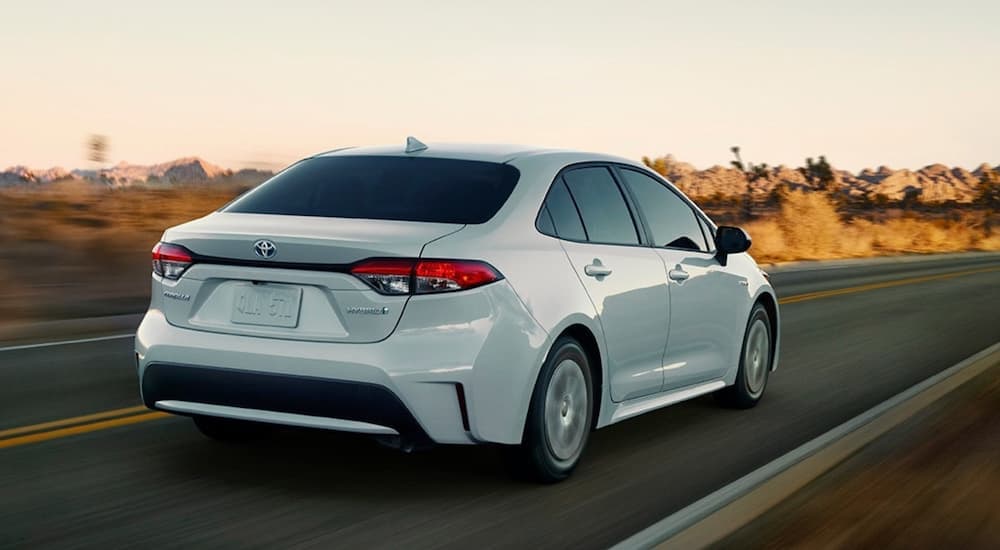 A white 2020 Toyota Corolla is shown from the rear driving down an open road.