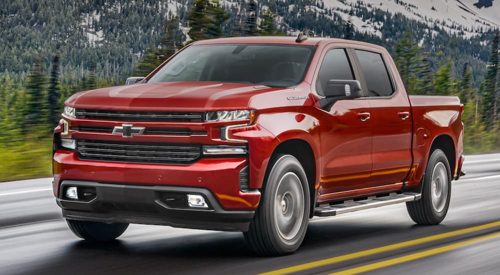 A red 2021 Chevy Silverado 1500 is shown from the side driving on an open road.