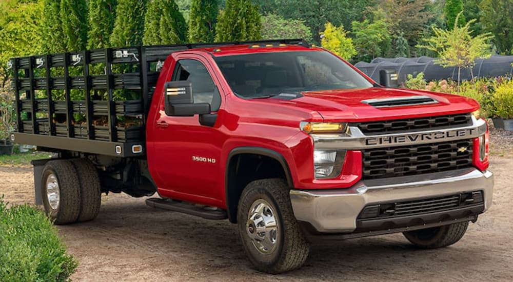 A red 2022 Chevy Silverado 3500HD Chassis Cab is shown at a plant nursery after leaving a Chevy dealer in Houston.