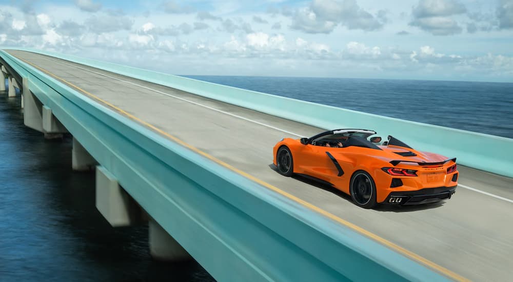 An orange 2022 Chevy Corvette is shown driving on a bridge after leaving a Houston Chevy dealer.