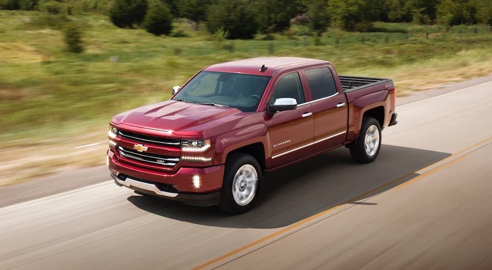A red 2018 Chevy Silverado 1500 is shown from the side driving on an open road.