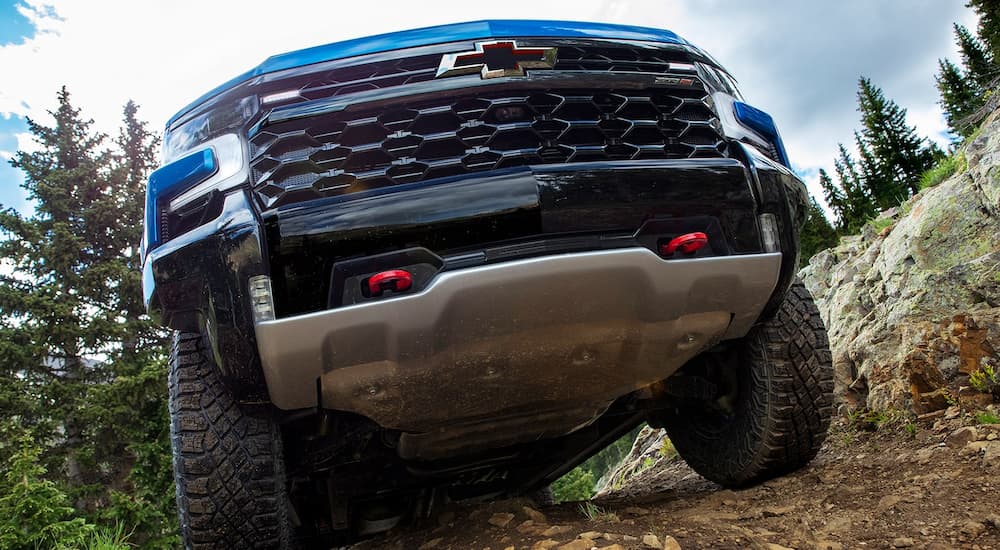 A blue 2022 Chevy Silverado ZR2 is shown from a low angle driving up a steep hill.