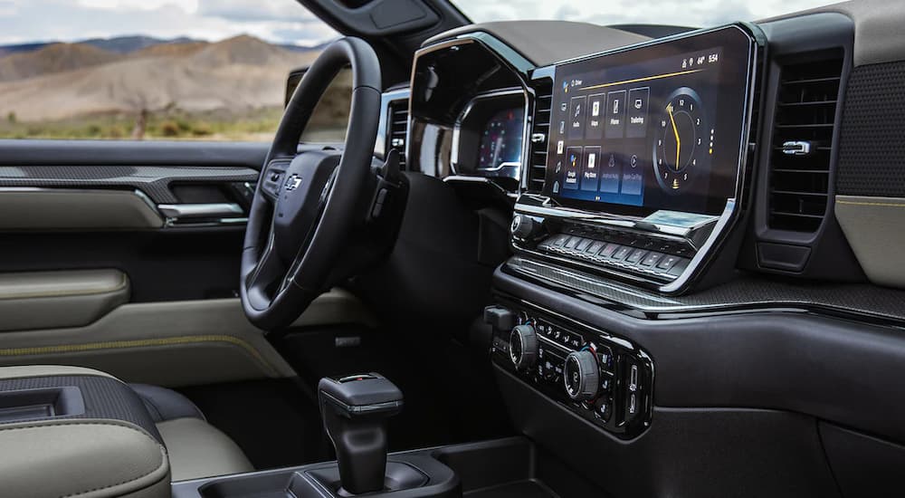 The black and tan accented interior of a 2022 Chevy Silverado ZR2 shows the infotainment screen and steering wheel near a Houston Chevy truck dealer.
