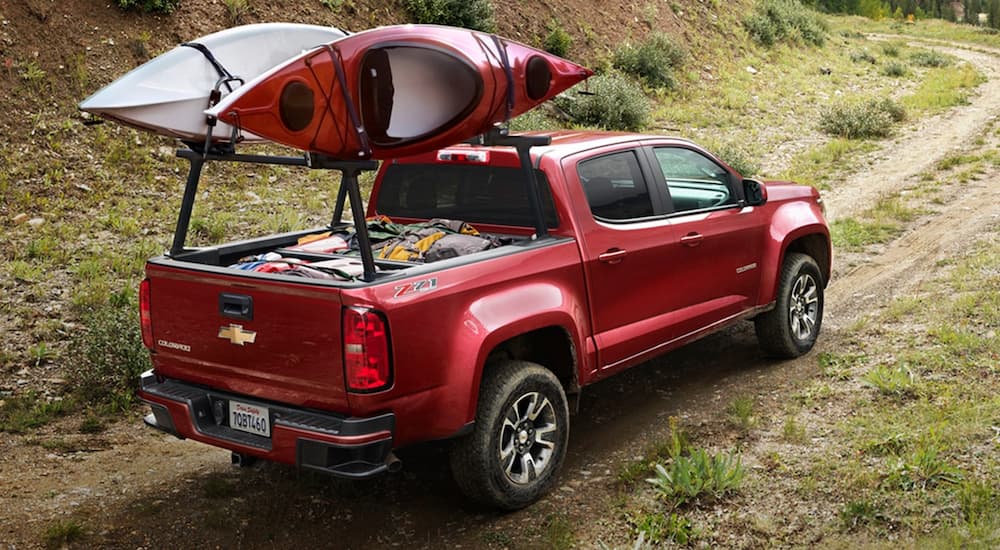 A red 2020 Chevy Colorado is shown from a rear angle with two kayaks secured on a rack and a full payload.