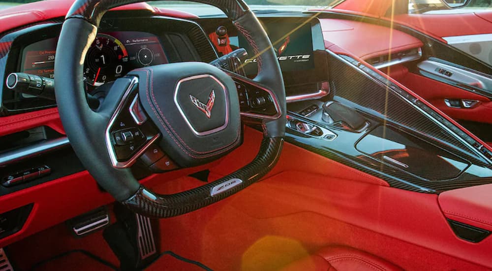 The red and black interior of a 2023 Chevy Corvette Z06 shows the steering wheel and controls.