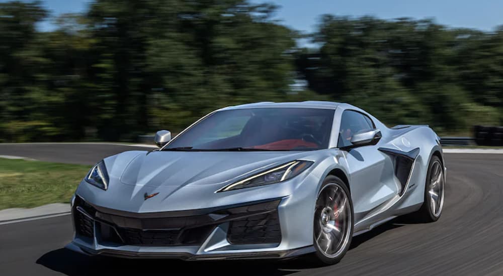 A silver 2023 Chevy Corvette Z06 is shown from the front driving on an open track.
