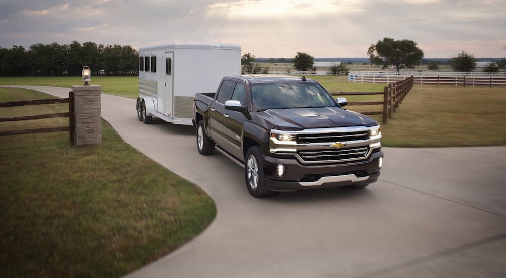 A black 2017 Chevy Silverado 1500 High Country is shown towing a horse trailer.