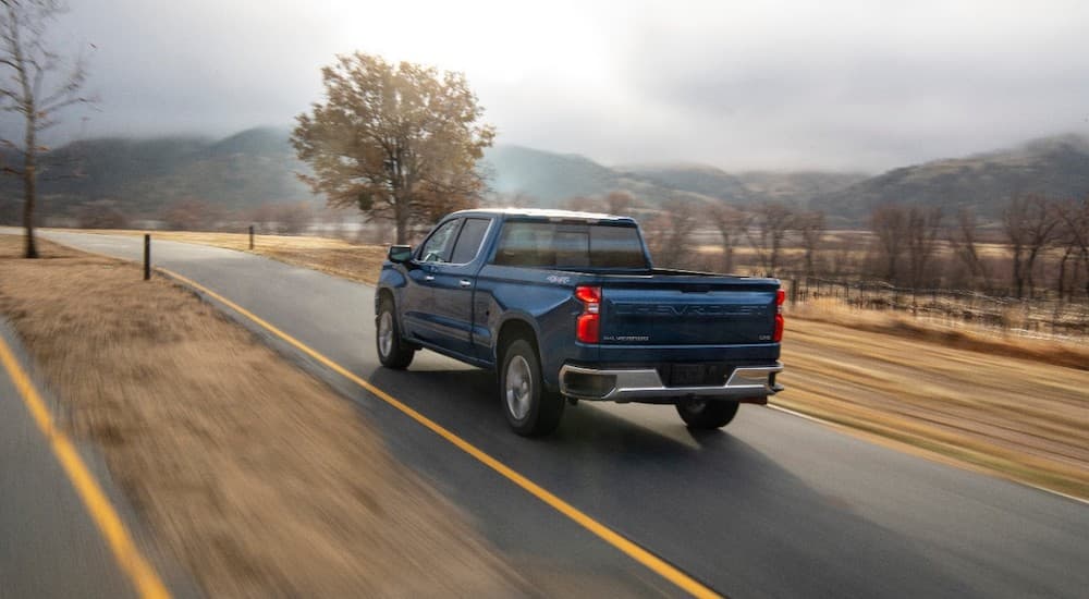 A blue 2020 Chevy Silverado 1500 is shown from the rear driving on an open road.