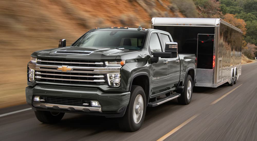 A green 2022 Chevy Silverado 2500 HD is shown from the front towing a closed trailer.