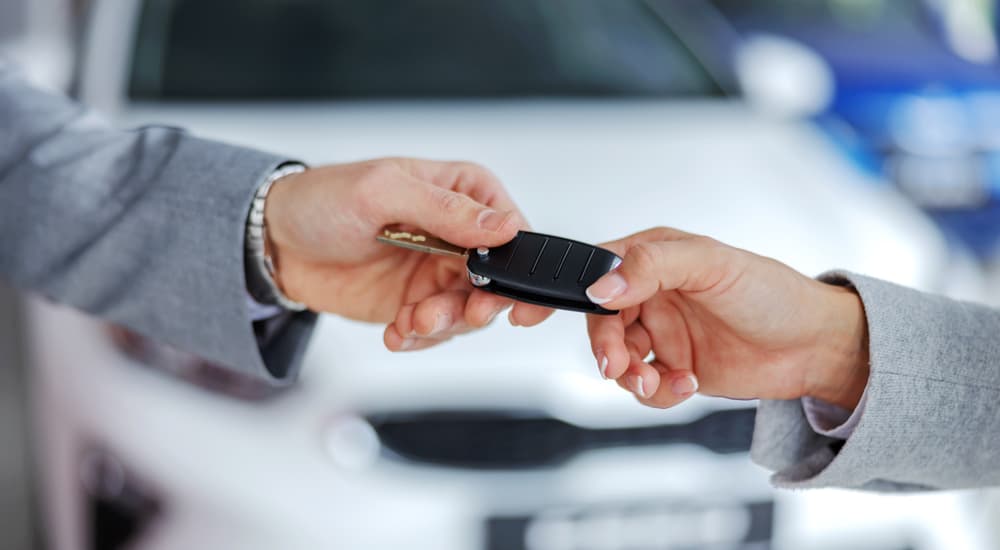 Se muestra a un vendedor y un cliente intercambiando la llave de un automóvil.