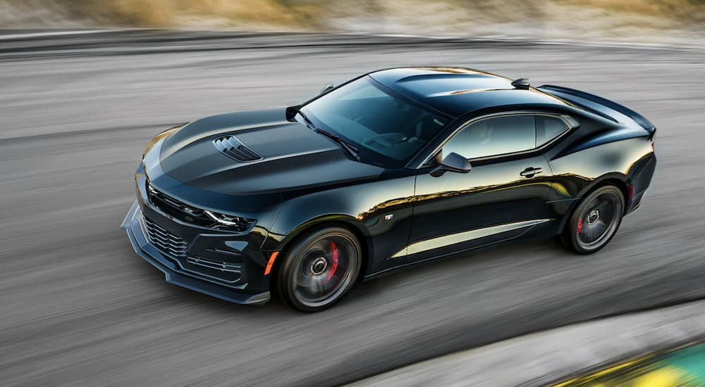 A black 2022 Chevy Camaro is shown from the side driving on a racetrack.