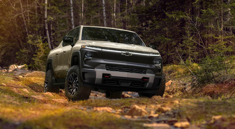 A tan 2024 Chevy Silverado EV Trail Boss is shown parked in the woods after visiting a Houston electric Silverado dealer.