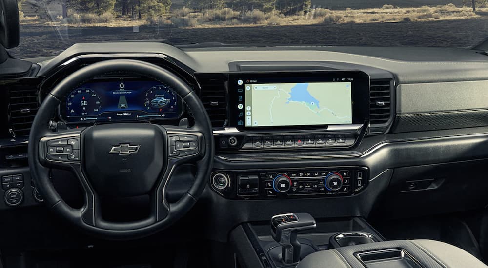 The black interior of a 2022 Chevy Silverado 1500 shows the steering wheel and infotainment screen.