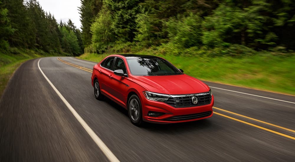 A red 2021 Volkswagen Jetta is shown from the front driving on an open road.