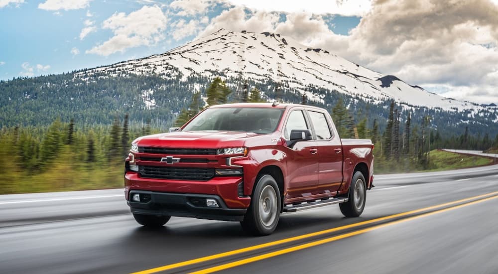A red 2020 Chevy Silverado 1500 Z71 is shown driving on a road with a mountain view.