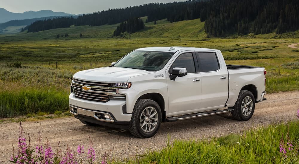 A white 2021 Chevy Silverado 1500 High Country is shown driving on a dirt road.