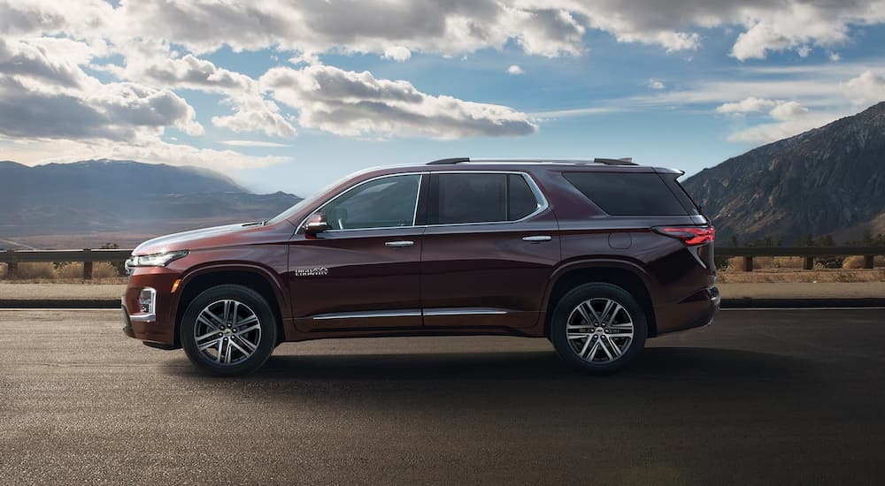 A brown 2023 Chevy Traverse High Country is shown from the side driving on an open highway.